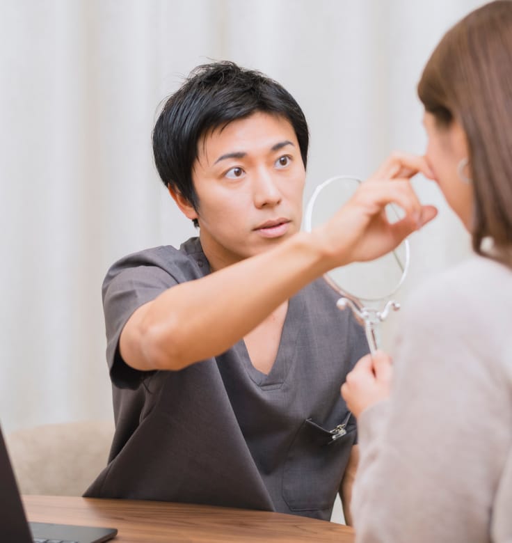 クリニックの診察室で、医師と患者が向き合い、表情や細部を確認しながら相談している場面